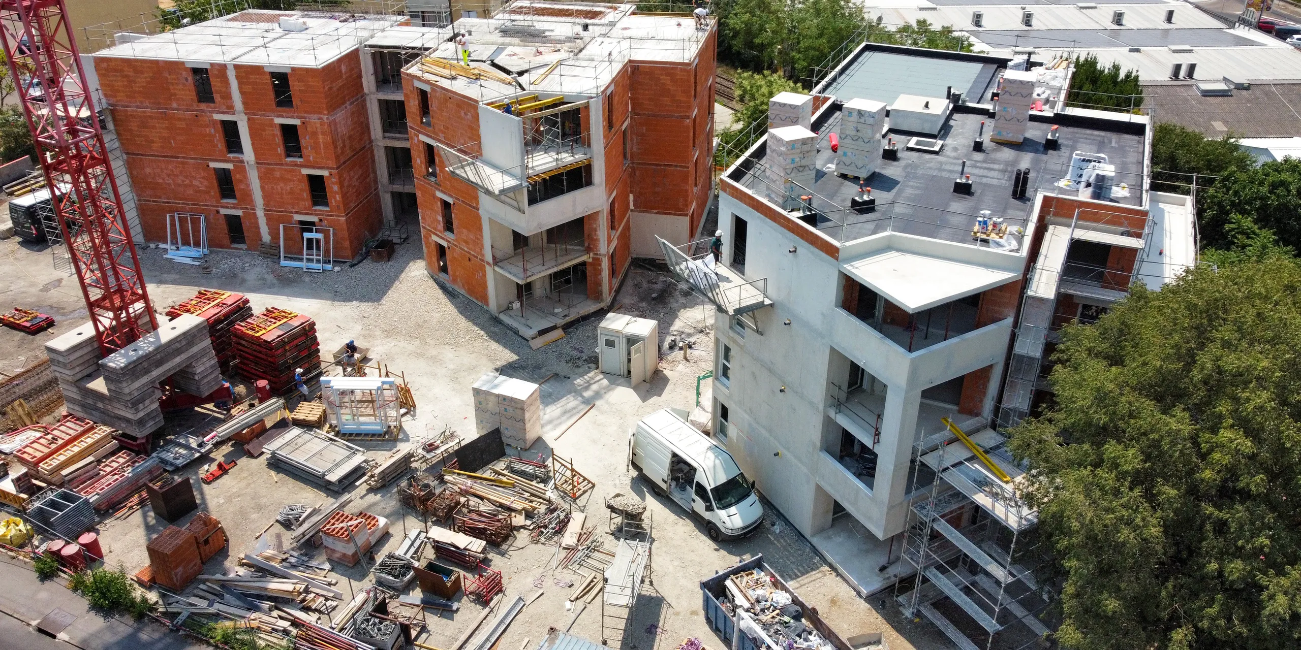 Chantier de logements collectifs à Alès vu du ciel, bâtiments en briques et voiles béton, banches stockées sur l’aire de chantier