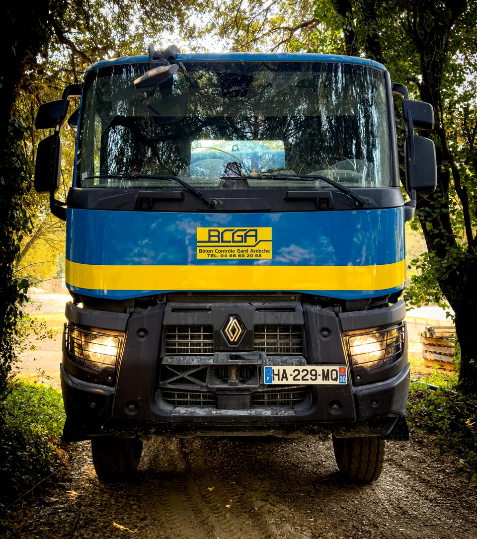 Camion-malaxeur BCGA vu de face, sous les arbres d’un site de chargement
