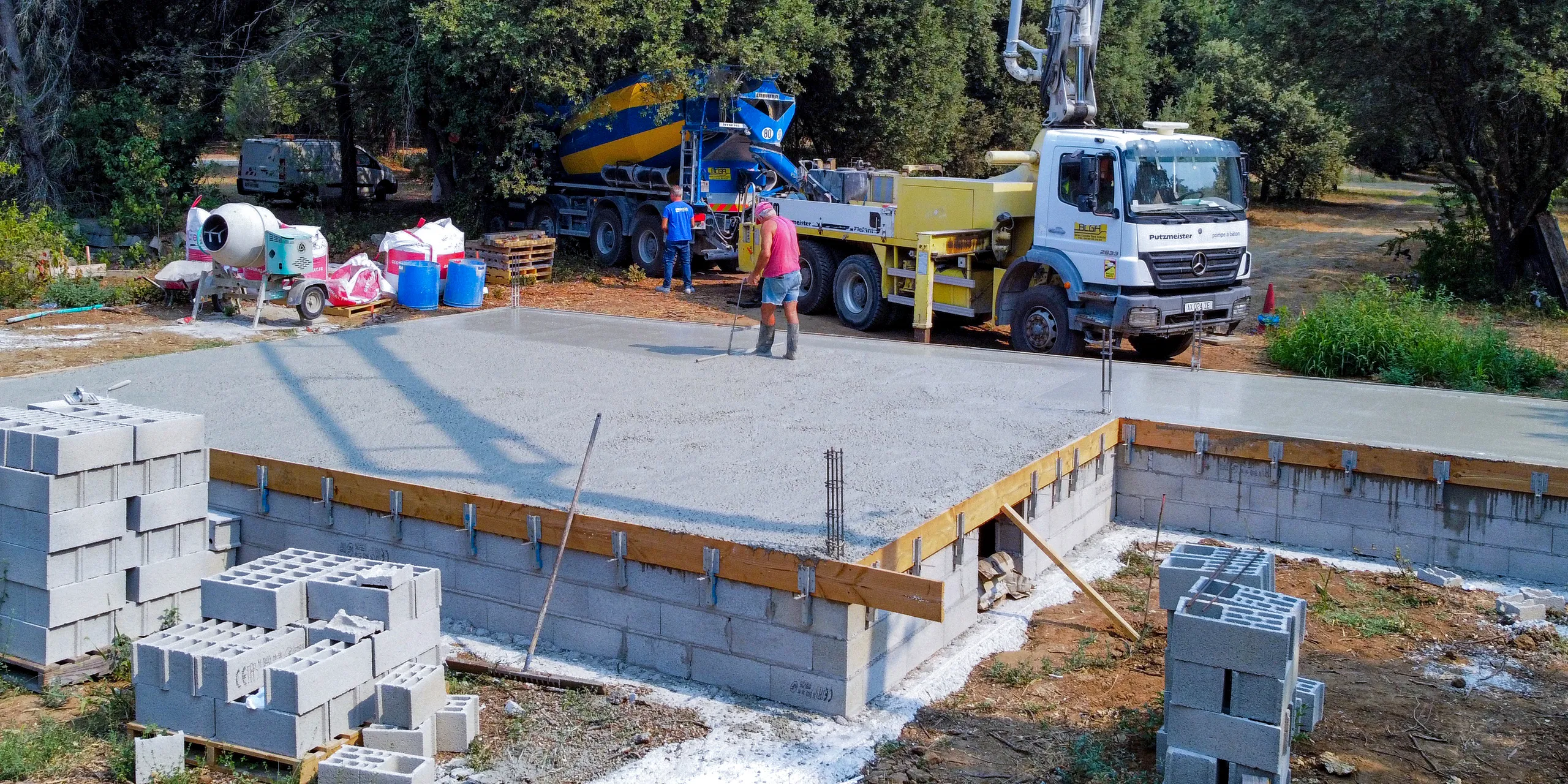 Dalle de maison individuelle en cours de finition à Uzès, camion-pompe et camion-malaxeur BCGA en arrière-plan